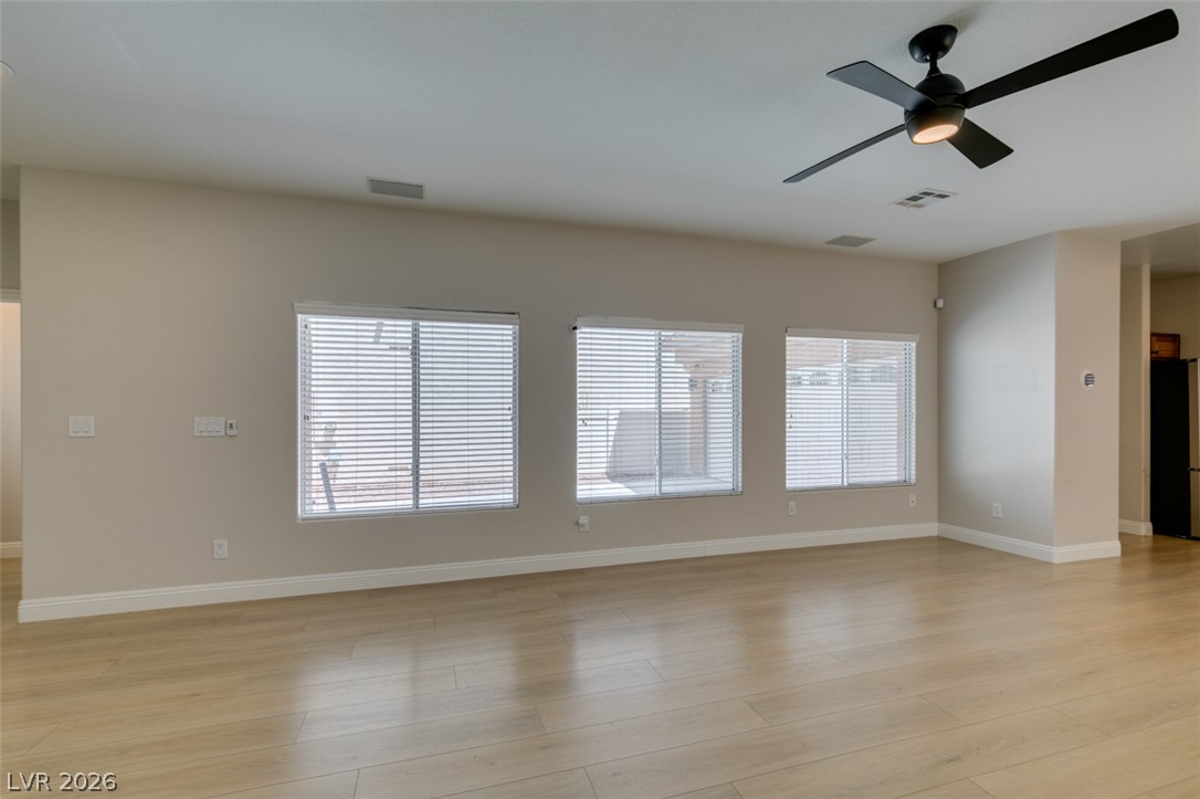 8909 Houston Ridge Avenue Las Vegas, NV 89178 - Photo 4 of 45 Blonde hardwood floors and a modern ceiling fan elevate this generously sized living space.