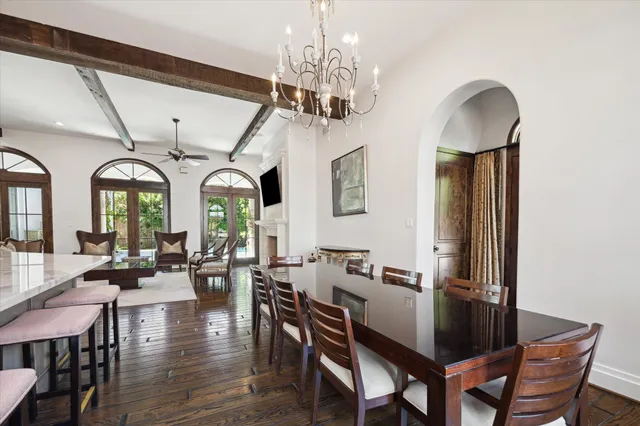 a dining room with wooden floor a chandelier a wooden table and chairs