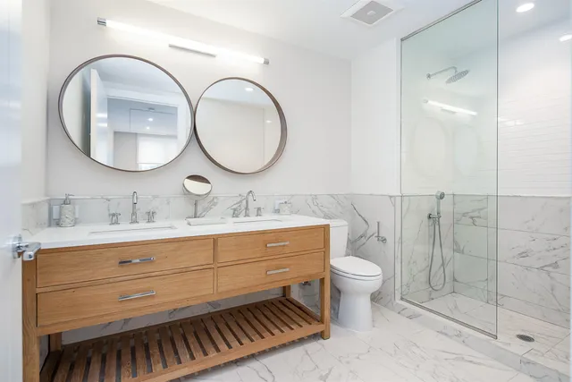 a bathroom with a double vanity sink mirror and toilet