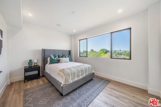 a bedroom with a bed lamp and a large window with outer view