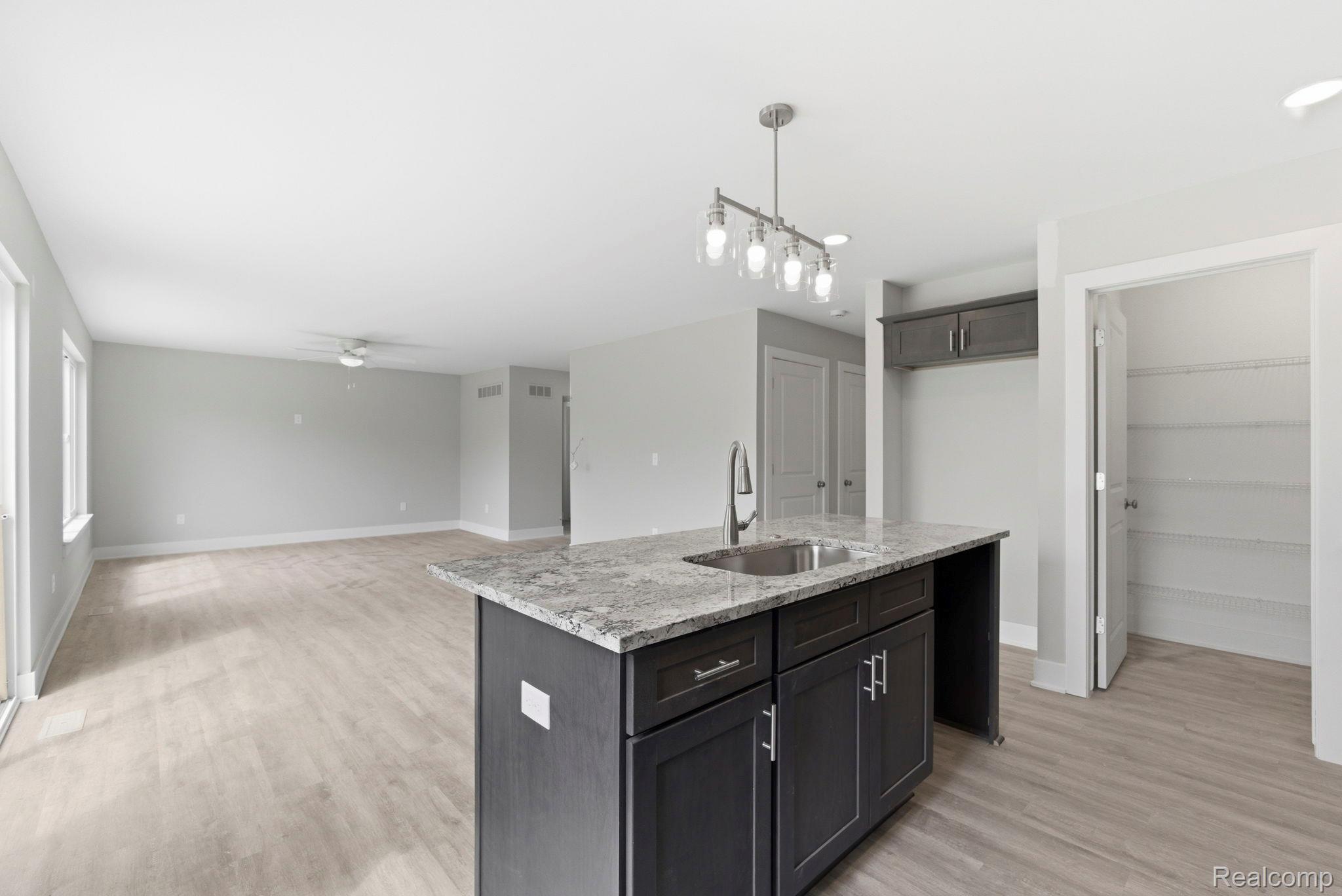 2361 Baltimore Davison, MI 48423 - Photo 31 of 31 Kitchen with an island with sink, light stone countertops, a ceiling fan, light wood finished floors, and open floor plan