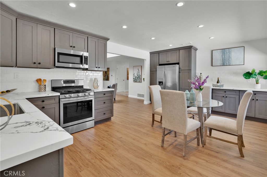4829 East Kenyon Place Orange, CA 92869 - Photo 12 of 42 a kitchen with stainless steel appliances a stove a sink a dining table and chairs