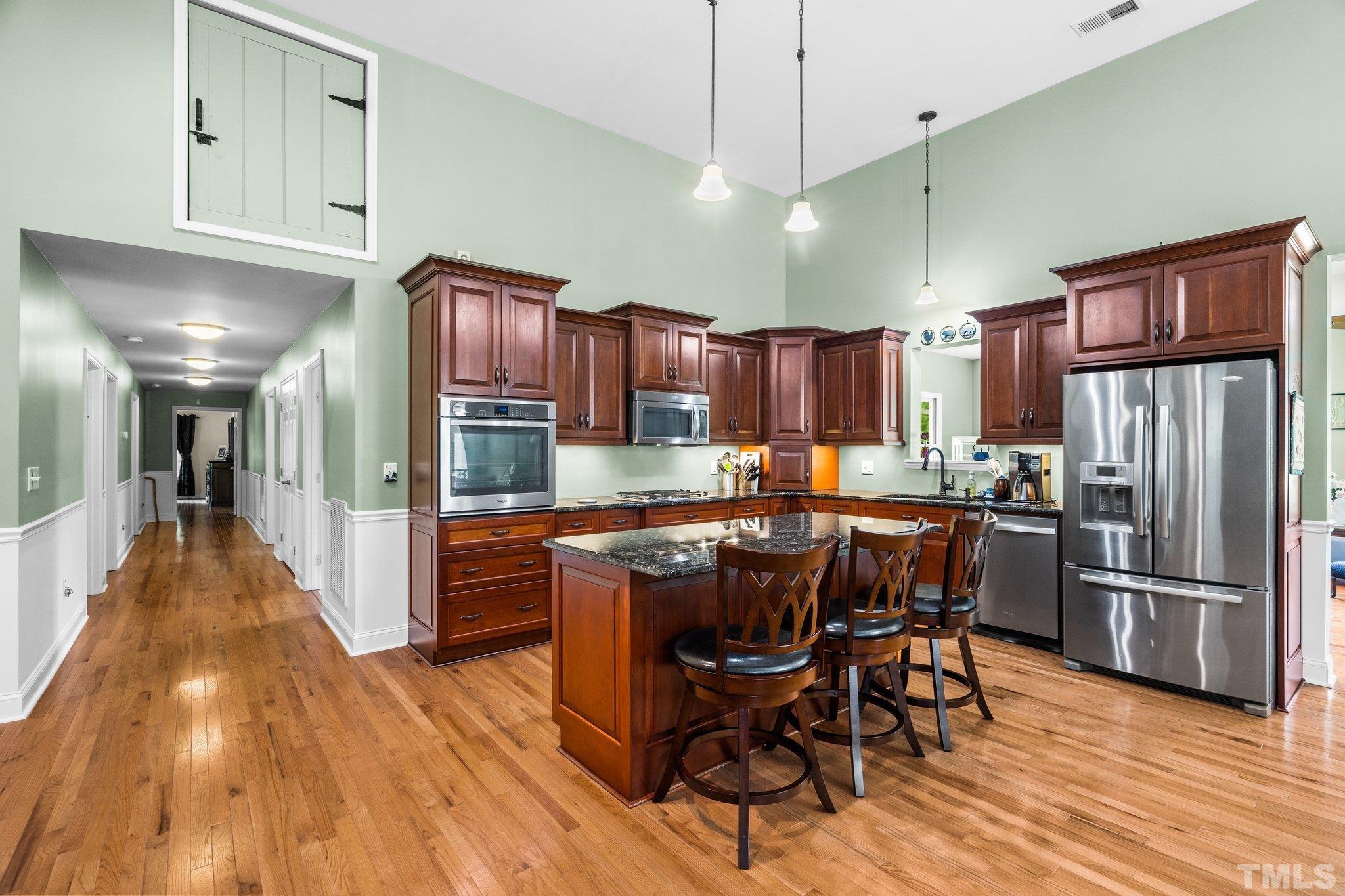 5012 Payton Drive Rougemont, NC 27572 - Photo 10 of 47 a kitchen with stainless steel appliances granite countertop wooden floors a refrigerator and chairs