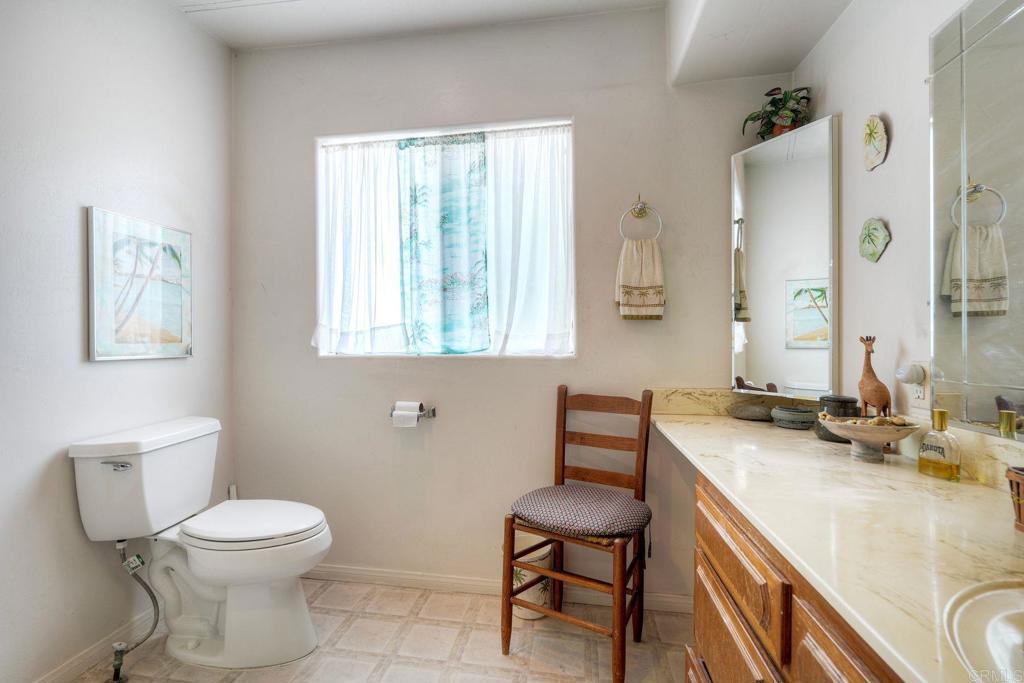 18218 Paradise Mountain Road Valley Center, CA 92082 - Photo 24 of 36 a bathroom with a granite countertop toilet a sink and a mirror