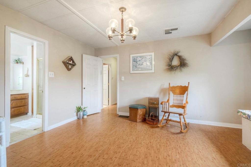 18218 Paradise Mountain Road Valley Center, CA 92082 - Photo 26 of 36 a spacious bedroom with a bed and a chandelier