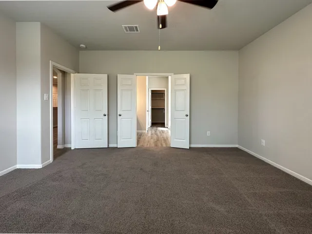 an empty room with chandelier fan and windows