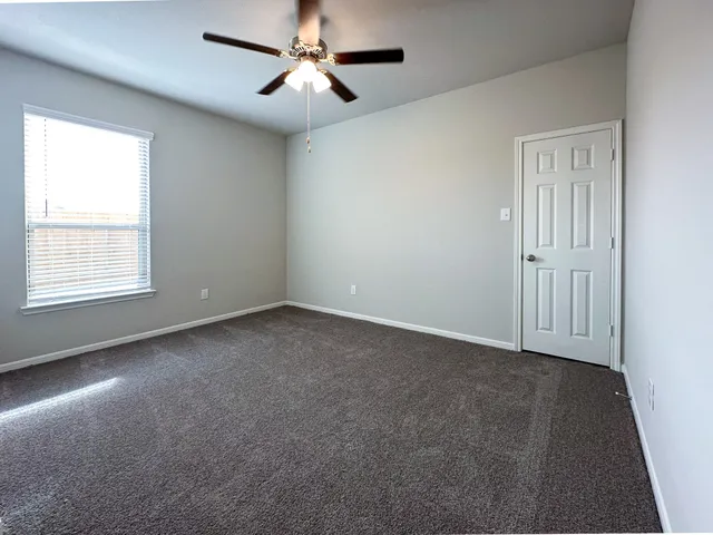 an empty room with windows and fan