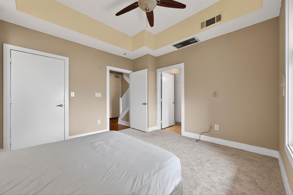 5055 Addison Circle, Unit 713 Addison, TX 75001 - Photo 18 of 40 Carpeted room featuring a ceiling fan, tray ceiling, multiple white panel doors, and a window with white trim