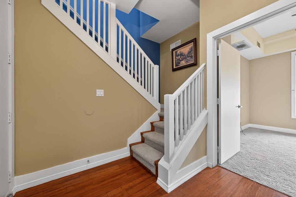 5055 Addison Circle, Unit 713 Addison, TX 75001 - Photo 23 of 40 Staircase with white balusters and carpeted treads, complemented by wood-finish flooring