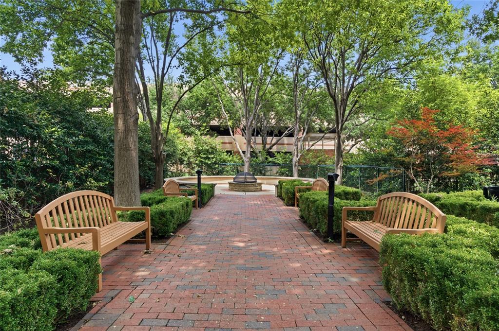 5055 Addison Circle, Unit 713 Addison, TX 75001 - Photo 35 of 40 Brick pathway bordered by manicured hedges and wooden benches, leading to a central water feature