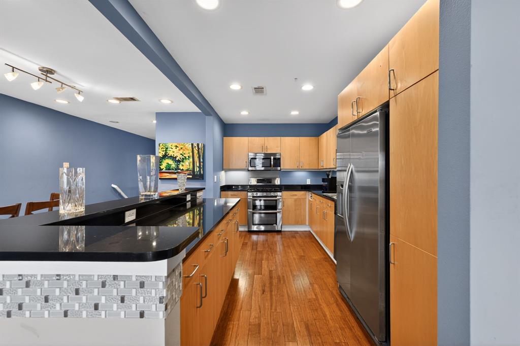 5055 Addison Circle, Unit 713 Addison, TX 75001 - Photo 6 of 40 a kitchen with stainless steel appliances granite countertop a sink a stove top oven a counter space and cabinets