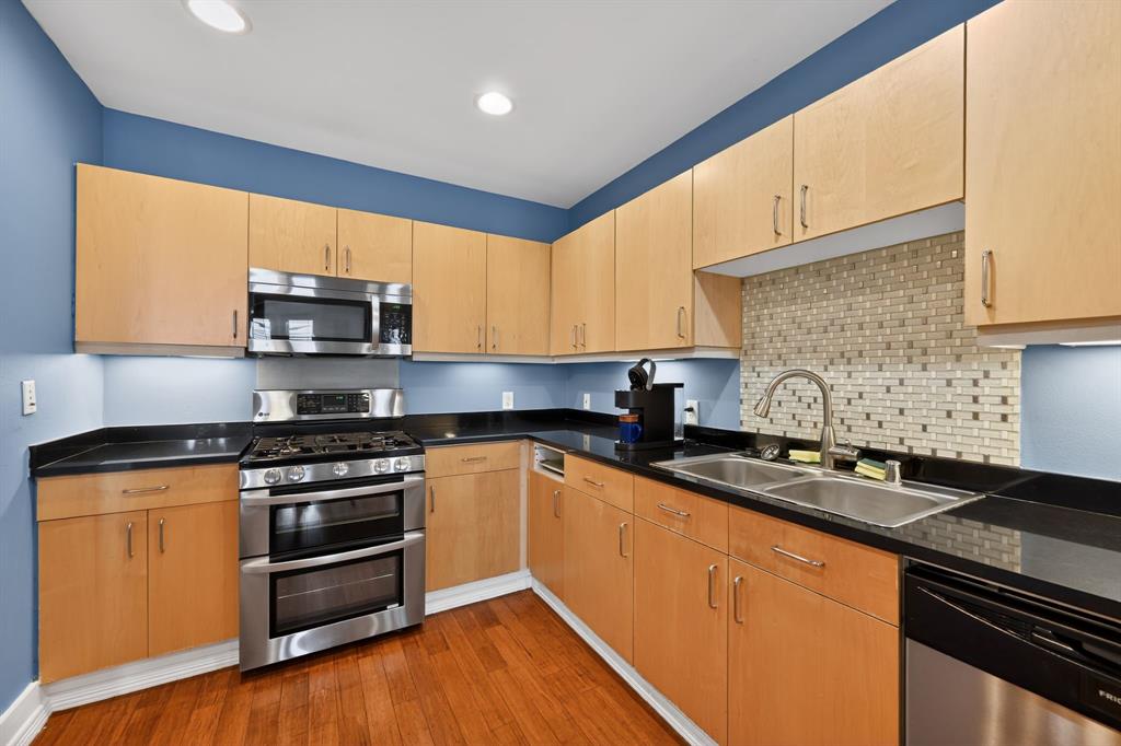5055 Addison Circle, Unit 713 Addison, TX 75001 - Photo 7 of 40 a kitchen with stainless steel appliances granite countertop a stove a sink and a microwave