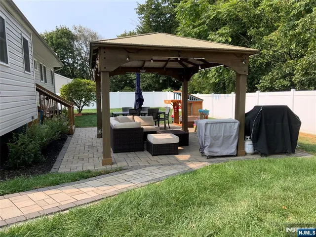 a view of a patio with table and chairs under an umbrella with a small yard