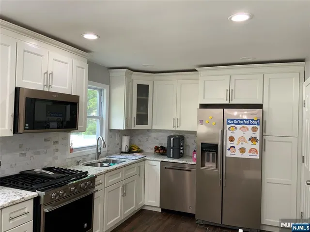 a kitchen with stainless steel appliances granite countertop a stove a refrigerator and a microwave