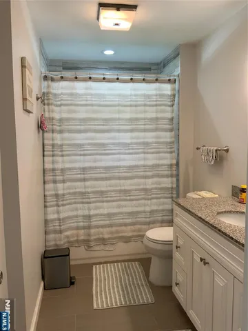a bathroom with a granite countertop toilet a sink and a shower