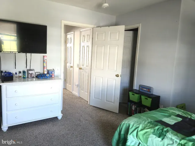 a bedroom with a bed and a flat tv screen on the dresser