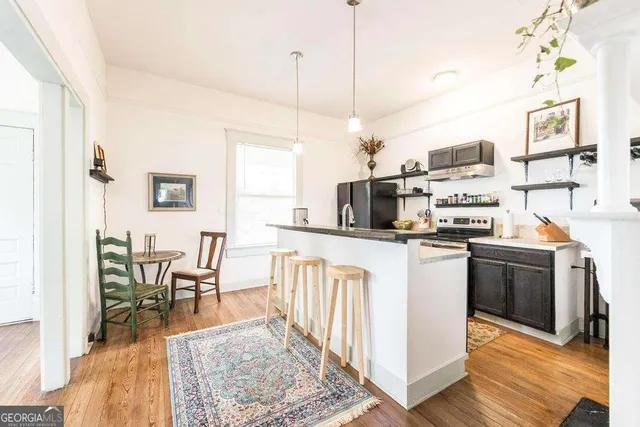 a kitchen with stainless steel appliances granite countertop a refrigerator a stove top oven a sink dishwasher and white cabinets with wooden floor