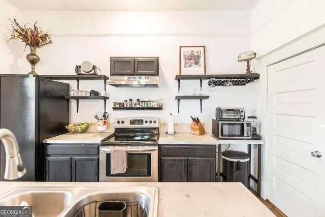 a kitchen with stainless steel appliances kitchen island granite countertop a refrigerator stove and sink