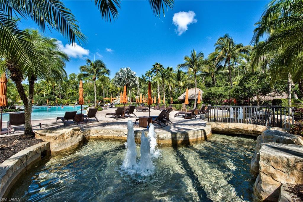 9102 Capistrano Street South, Unit 7209 Naples, FL 34113 - Photo 21 of 25 a view of a swimming pool with chairs and palm tree
