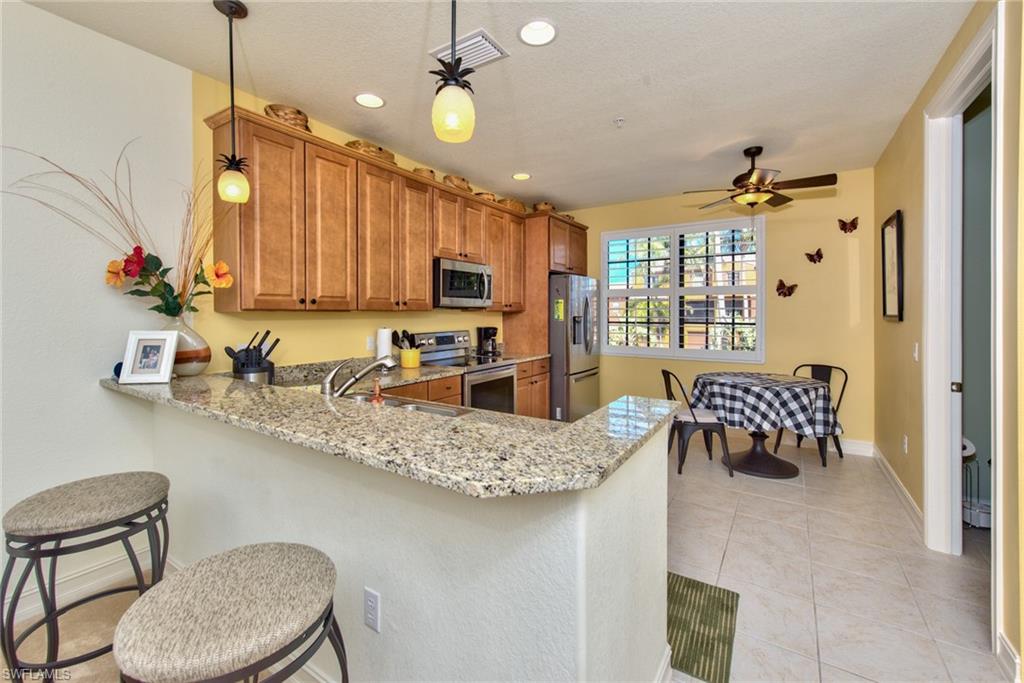 9102 Capistrano Street South, Unit 7209 Naples, FL 34113 - Photo 7 of 25 a kitchen with a sink dishwasher a stove a microwave oven with a dining table and chairs