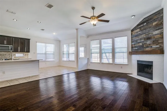 a view of an empty room with wooden floor and a kitchen