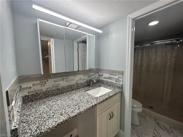a bathroom with a granite countertop sink toilet and shower