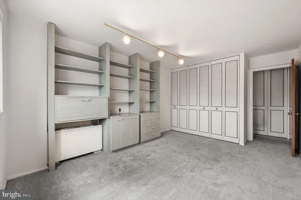 a view of an empty room with cabinet and mirrors