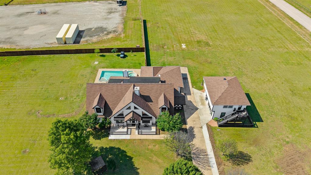 12240 Wellington Road Ponder, TX 76259 - Photo 38 of 40 Expansive property featuring a main residence with a gabled roofline, a detached secondary structure, a swimming pool, and extensive grassy areas