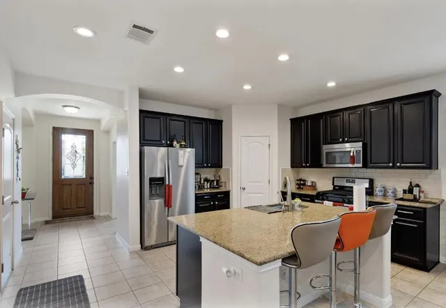 a kitchen with stainless steel appliances granite countertop a stove a sink and a refrigerator
