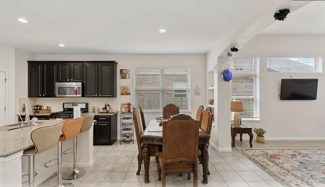a kitchen with stainless steel appliances kitchen island granite countertop a refrigerator and a stove top oven with white cabinets
