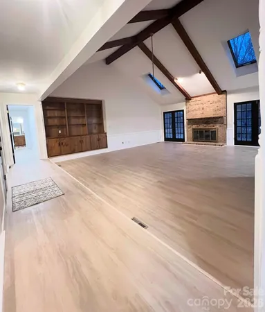 a view of an empty room with a fireplace and a window