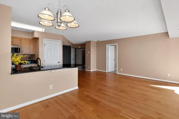 a view of an empty room with wooden floor and chandelier