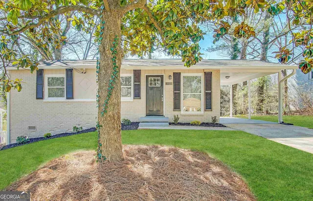 a view of a house with a yard and large tree
