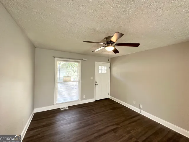 a view of empty room with wooden floor and fan