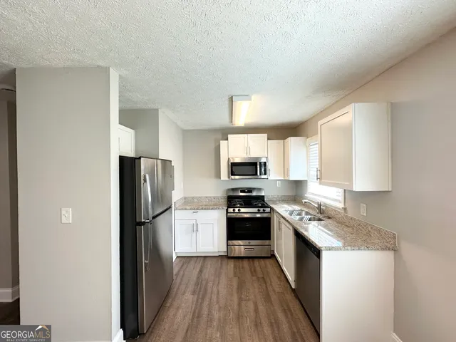 a kitchen with a refrigerator a stove top oven and wooden floor