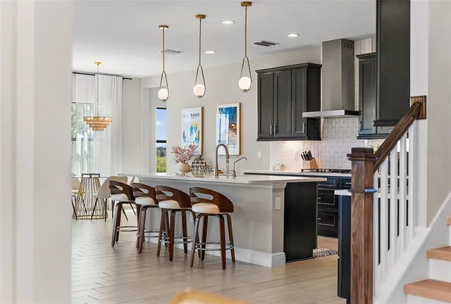 a kitchen with stainless steel appliances granite countertop a stove a sink a refrigerator and a dining table with wooden floor