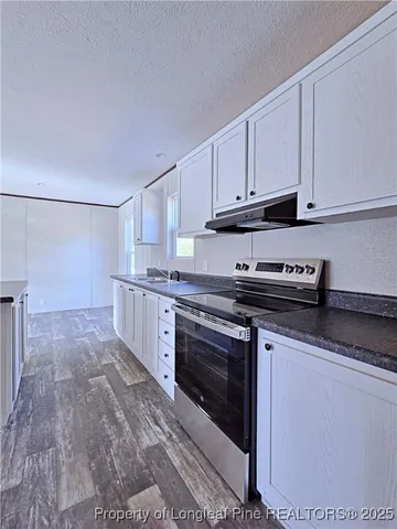 a kitchen with granite countertop a stove sink and cabinets