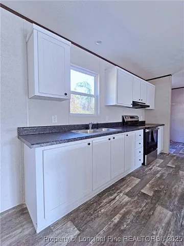 a kitchen with granite countertop a sink cabinets and stainless steel appliances