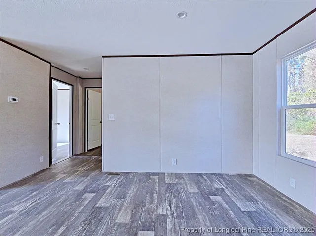 an empty room with wooden floor and windows with curtains