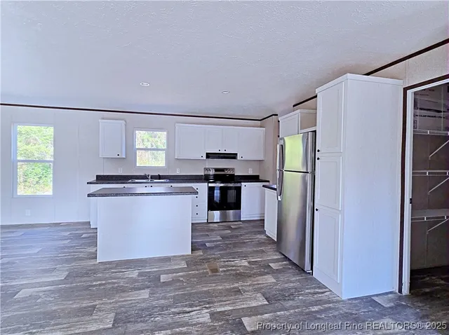 a kitchen with granite countertop a refrigerator and a stove top oven