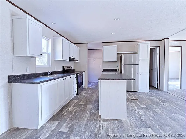 a kitchen with granite countertop a refrigerator stove top oven and sink