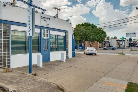 a view of a building with cars park side of road