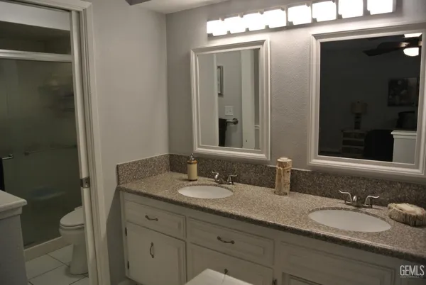 a bathroom with a granite countertop sink a toilet and a mirror