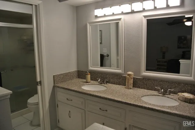 a bathroom with a granite countertop sink a toilet and a mirror