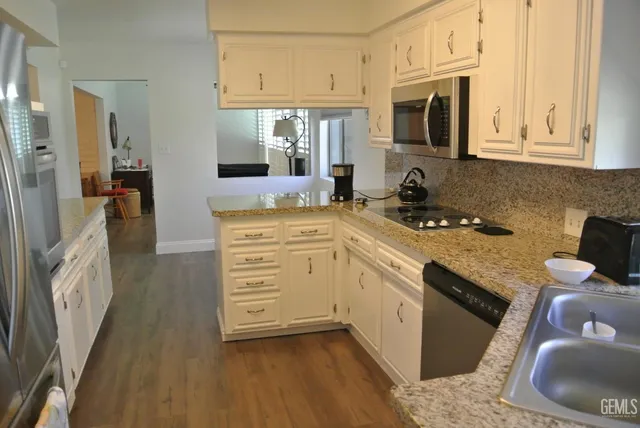 a kitchen with granite countertop a sink stove and cabinets