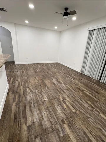an empty room with wooden floor a ceiling fan and staircase