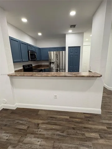 a view of kitchen with stainless steel appliances granite countertop wooden cabinets and a sink