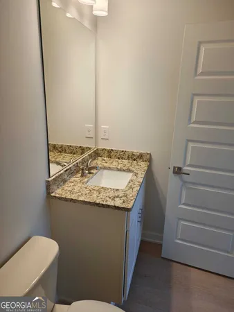 a bathroom with a granite countertop sink and a toilet