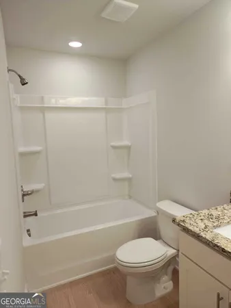 a bathroom with a granite countertop toilet a sink and a bathtub
