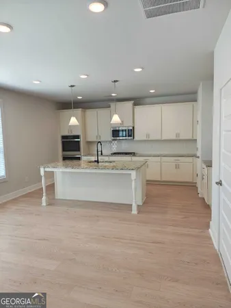 a large white kitchen with stainless steel appliances granite countertop a stove and a sink